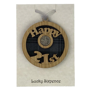 A unique keepsake gift with a Scottish twist.  The sixpence is mounted onto a round hanging oak veneered wood with tartan inserts, mounted on card and packaged in clear cellophane packets.  'Happy 21st' is laser cut into the wooden hanging.