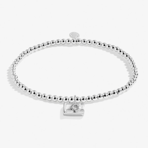 Joma jewellery stretch beaded bracelet in sterling silver with hanging camera charm presented o a foil stamped sentiment card.