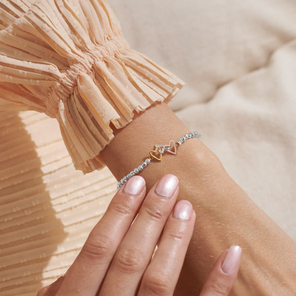 Joma jewellery stretch beaded bracelet with three heart charms in silver, gold and rose gold.