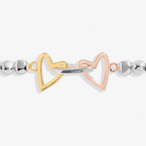 Joma jewellery stretch beaded bracelet with three heart charms in silver, gold and rose gold.