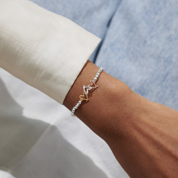 Joma Jewellery beaded bracelet with three open heart charms in silver, gold and rose gold.