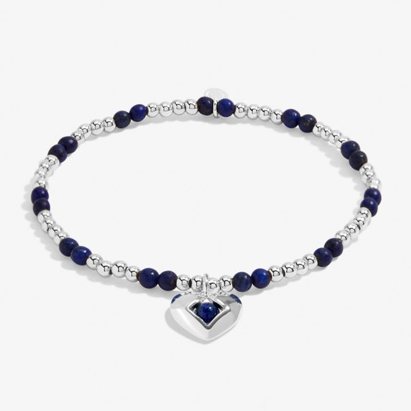 Joma Jewellery stretch beaded birthstone bracelet with blue semi-precious gemstones and a silver plated hanging heart charm.