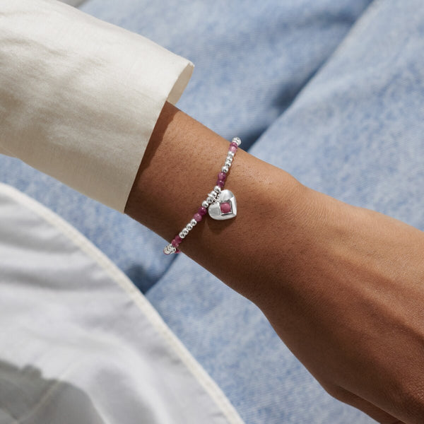 Joma Jewellery October birthstone stretch bracelet with pink semi-precious gemstones and silver hanging heart charm.