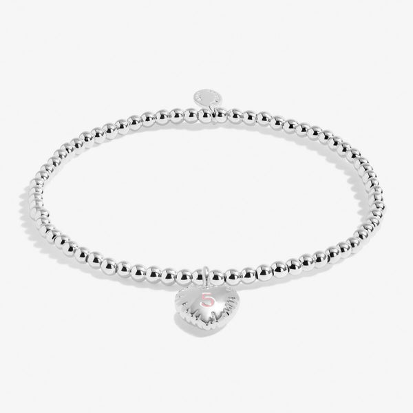 Joma jewellery girls birthday bracelet with silver plated beads and a hanging heart charm with a number 5 stamped in pink.