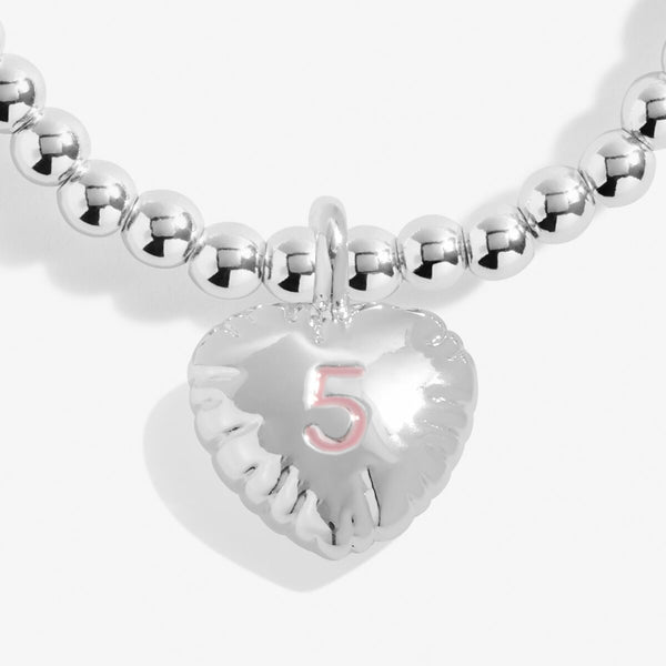 Joma jewellery girls birthday bracelet with silver plated beads and a hanging heart charm with a number 5 stamped in pink.