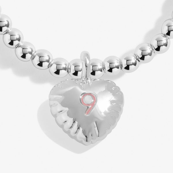 Joma girls birthday bracelet with silver plated beads and a hanging heart charm with '9' stamped in pink.