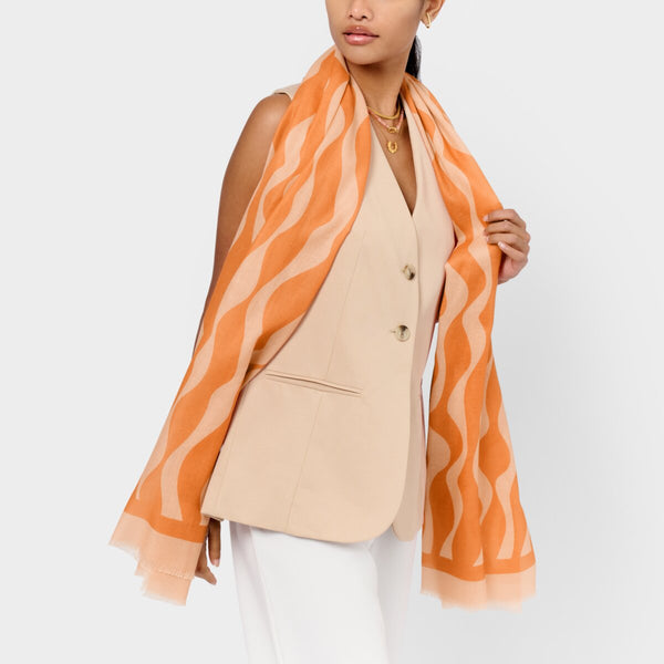 Katie Loxton ripple wave printed scarf in orange and pink with stylish frayed edges and lightweight fabric.